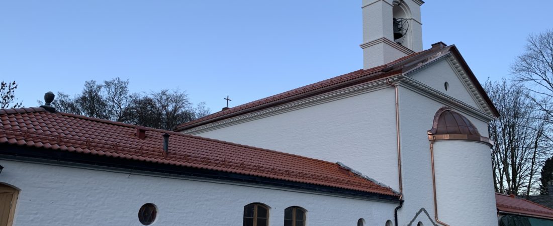 Et hvitt kirkebygg med rødt tak og nye beslag.